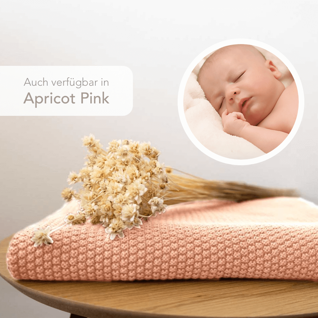 Strickdecke von Kinderzimmer.de in apricot-pink, dargestellt mit schlafendem Baby